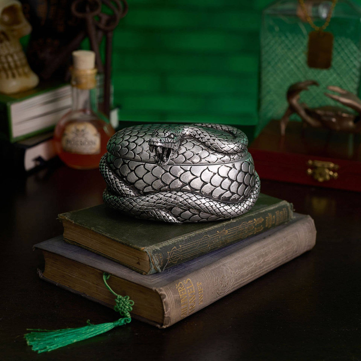 Boite ovale serpent de la marque harry potter, dans un decor de vieille librairie