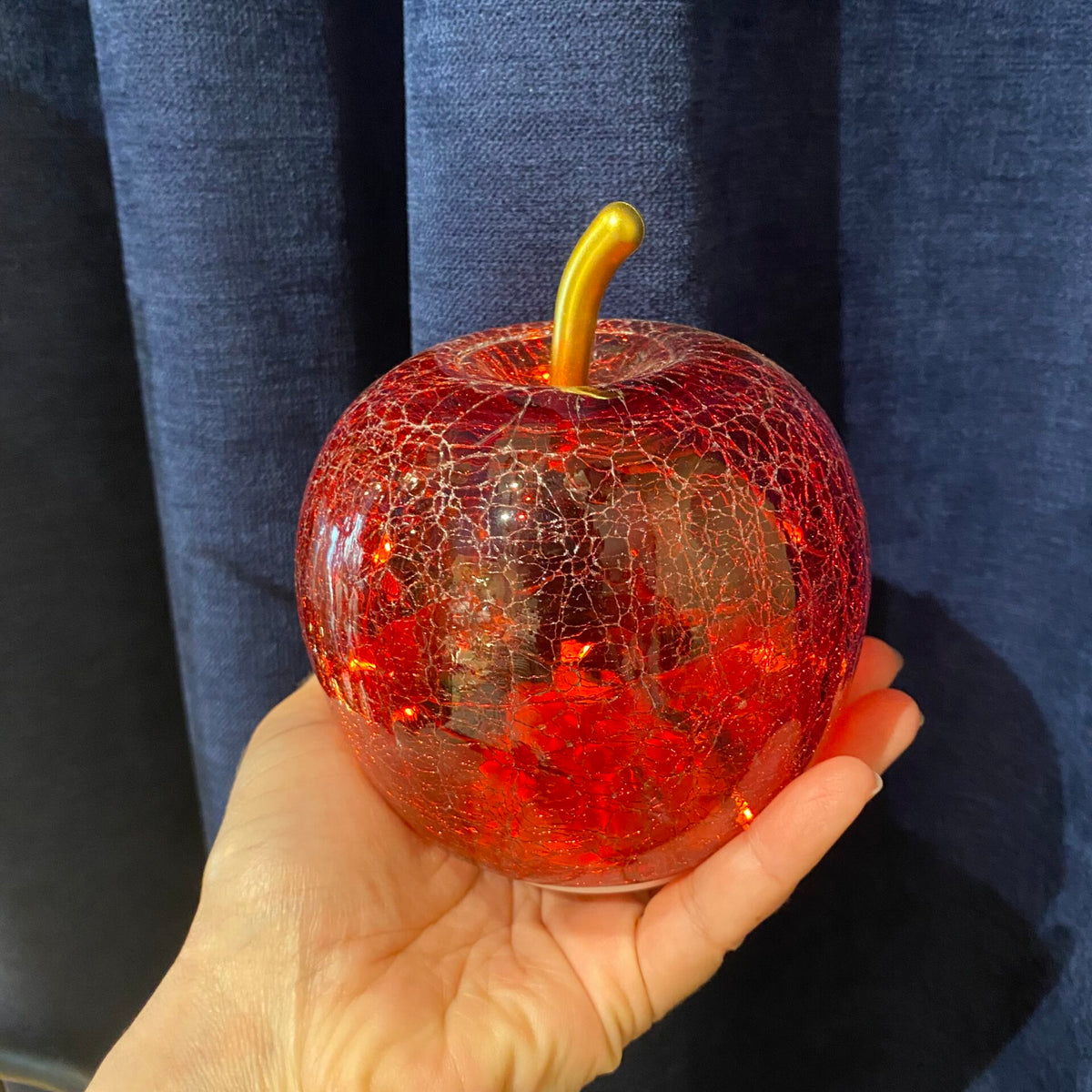 Pomme rouge en verre craquelé dans une main