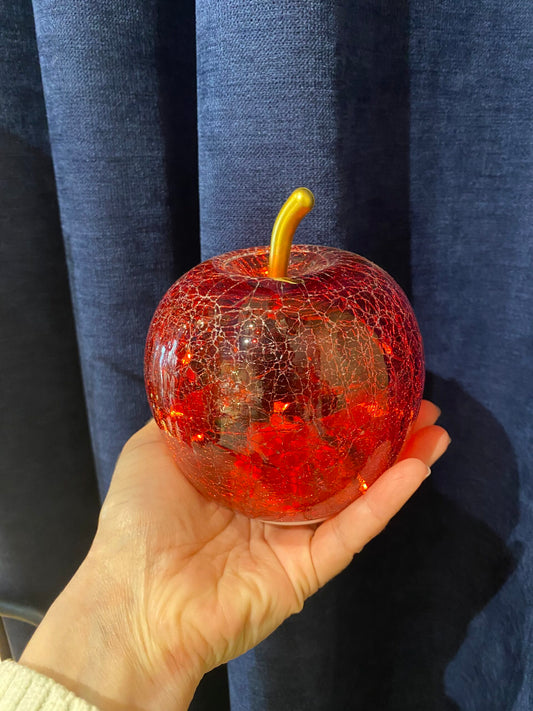 Pomme rouge en verre craquelé dans une main