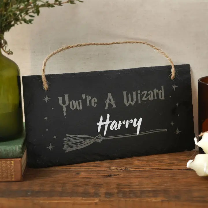 ardoise rectangulaire écrite You are a wizard Harry posée sur une table en bois